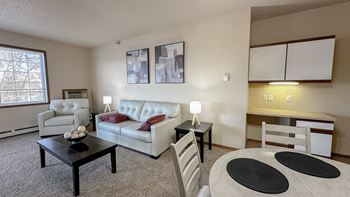 a living room with white couches and chairs and a dining room table